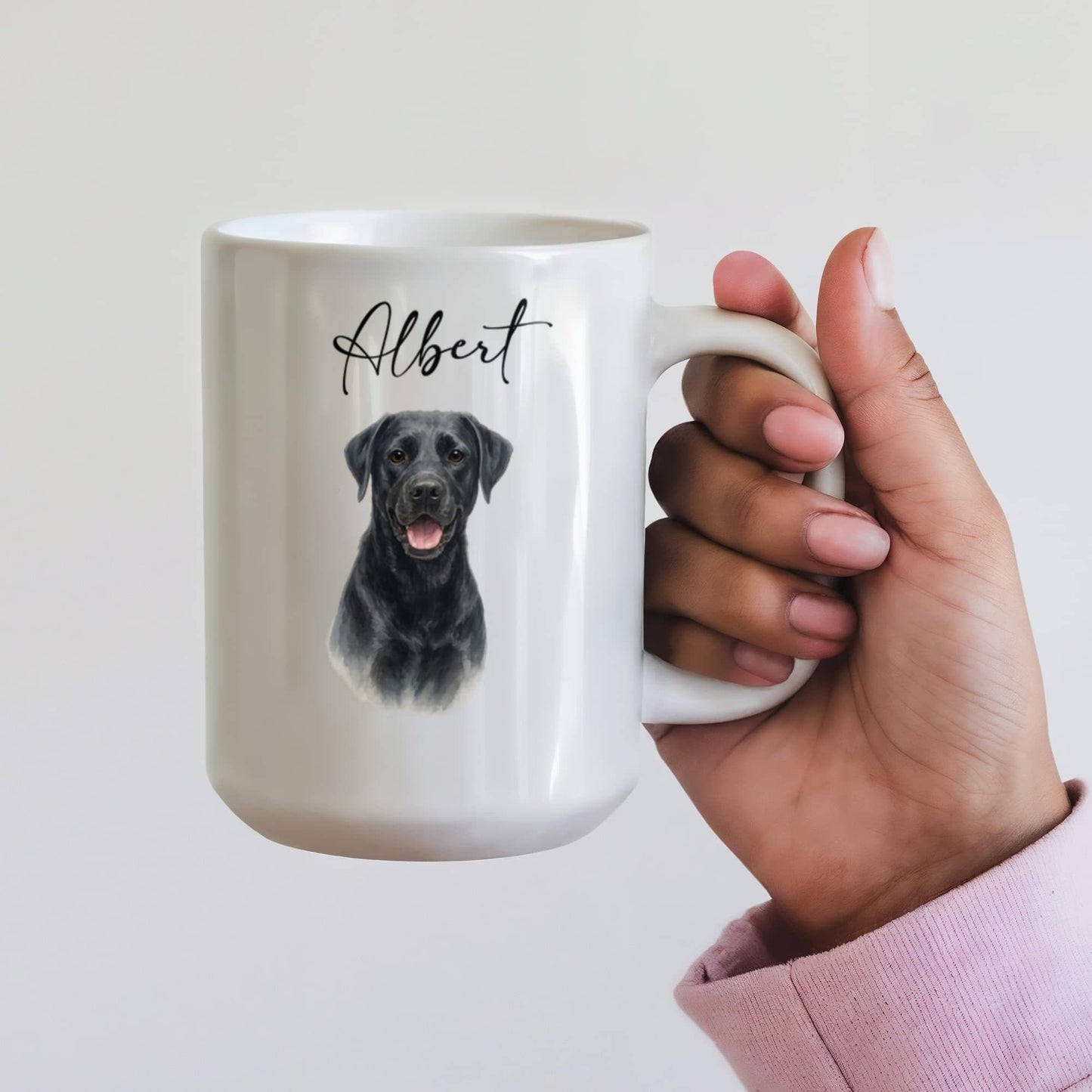 White mug with a black dog illustration and 'Albert' text, held by a hand against a light background