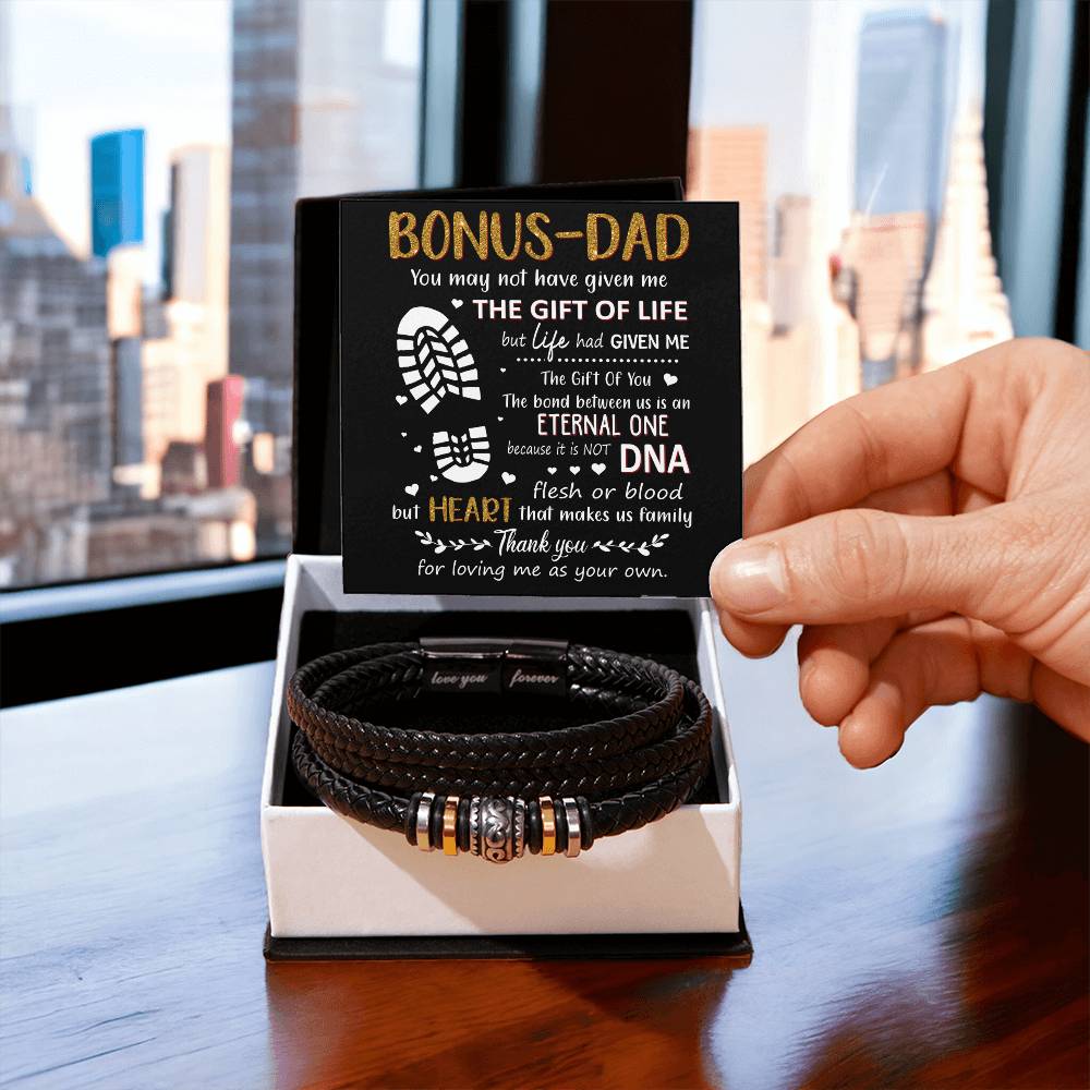Hand holding a heartfelt card for a bonus dad next to a stylish black bracelet, perfect for showing appreciation and love