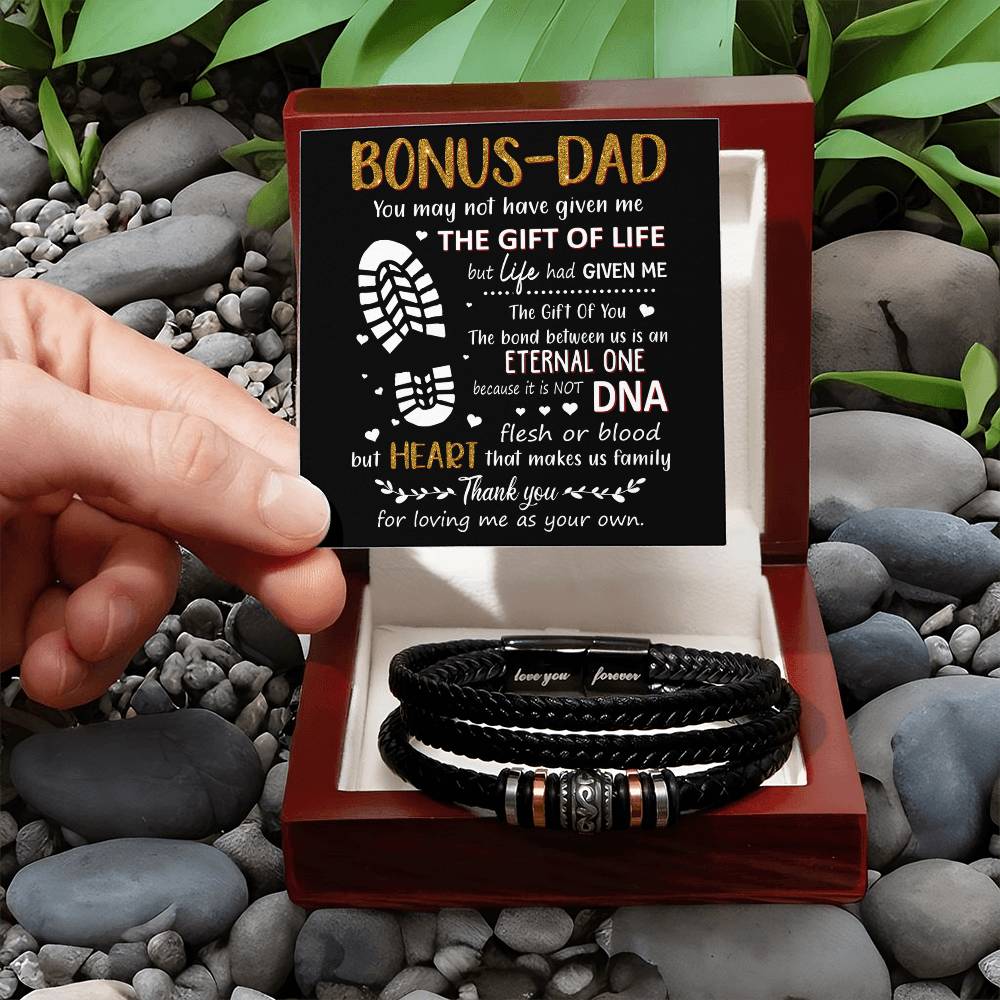 Hand holding a heartfelt card for a bonus dad next to a stylish black bracelet, perfect for showing appreciation and love