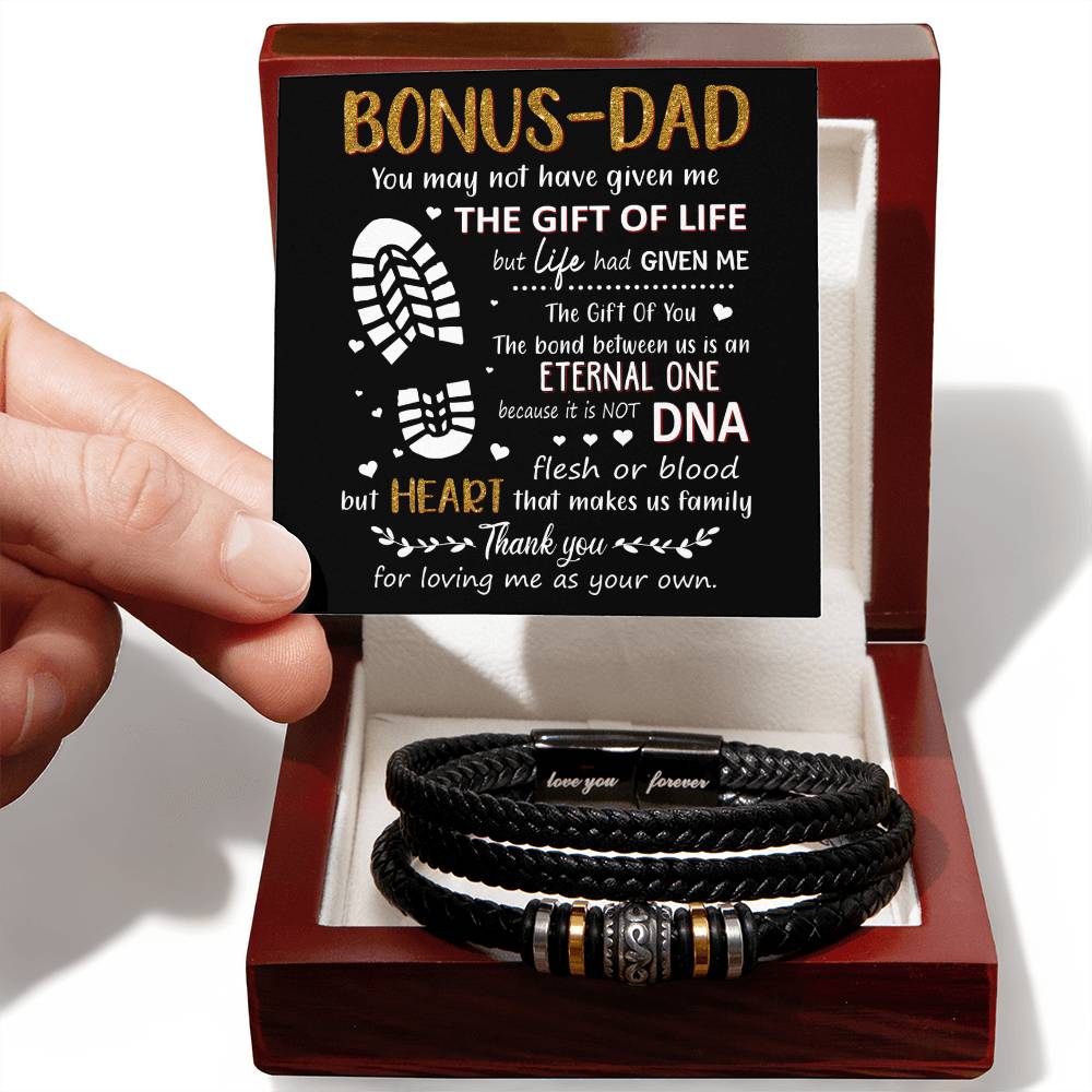 Hand holding a heartfelt card for a bonus dad next to a stylish black bracelet, perfect for showing appreciation and love