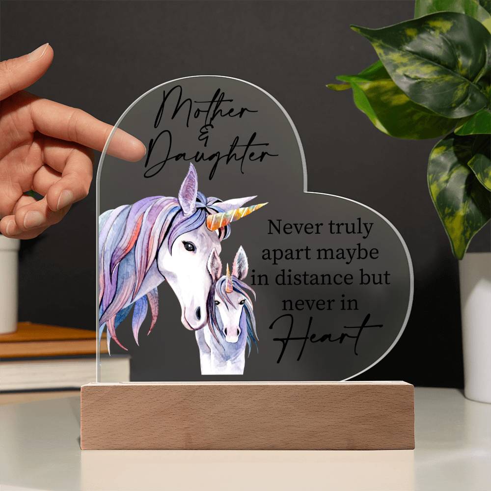 a person holding a glass heart with a picture of a unicorn on it