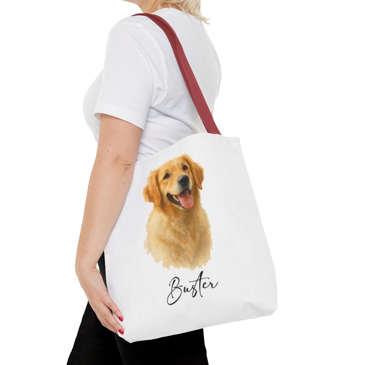 Person holding a tote bag with a dog illustration and name 'Buster' on a white background