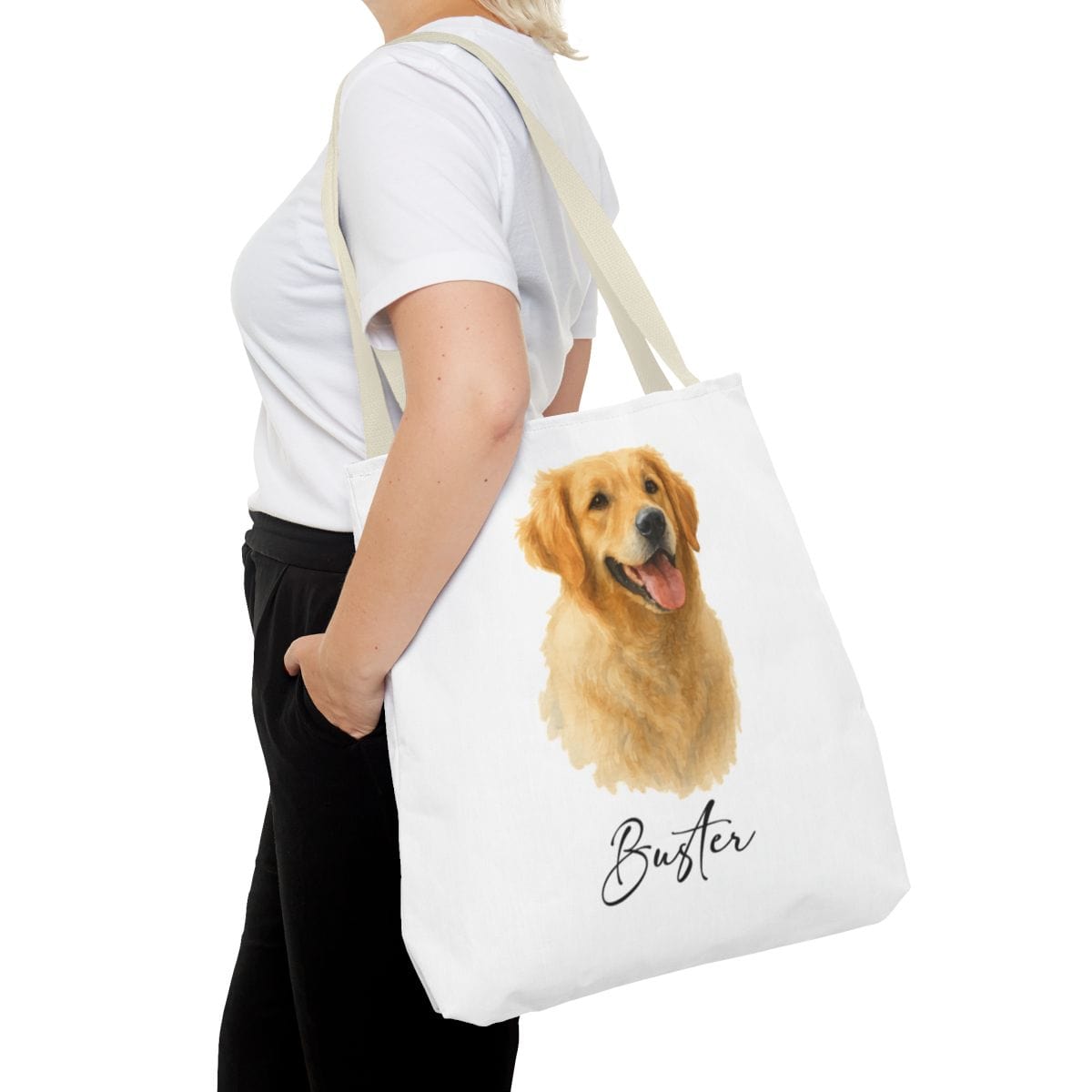 Person holding a tote bag with a dog illustration and name 'Buster' on a white background