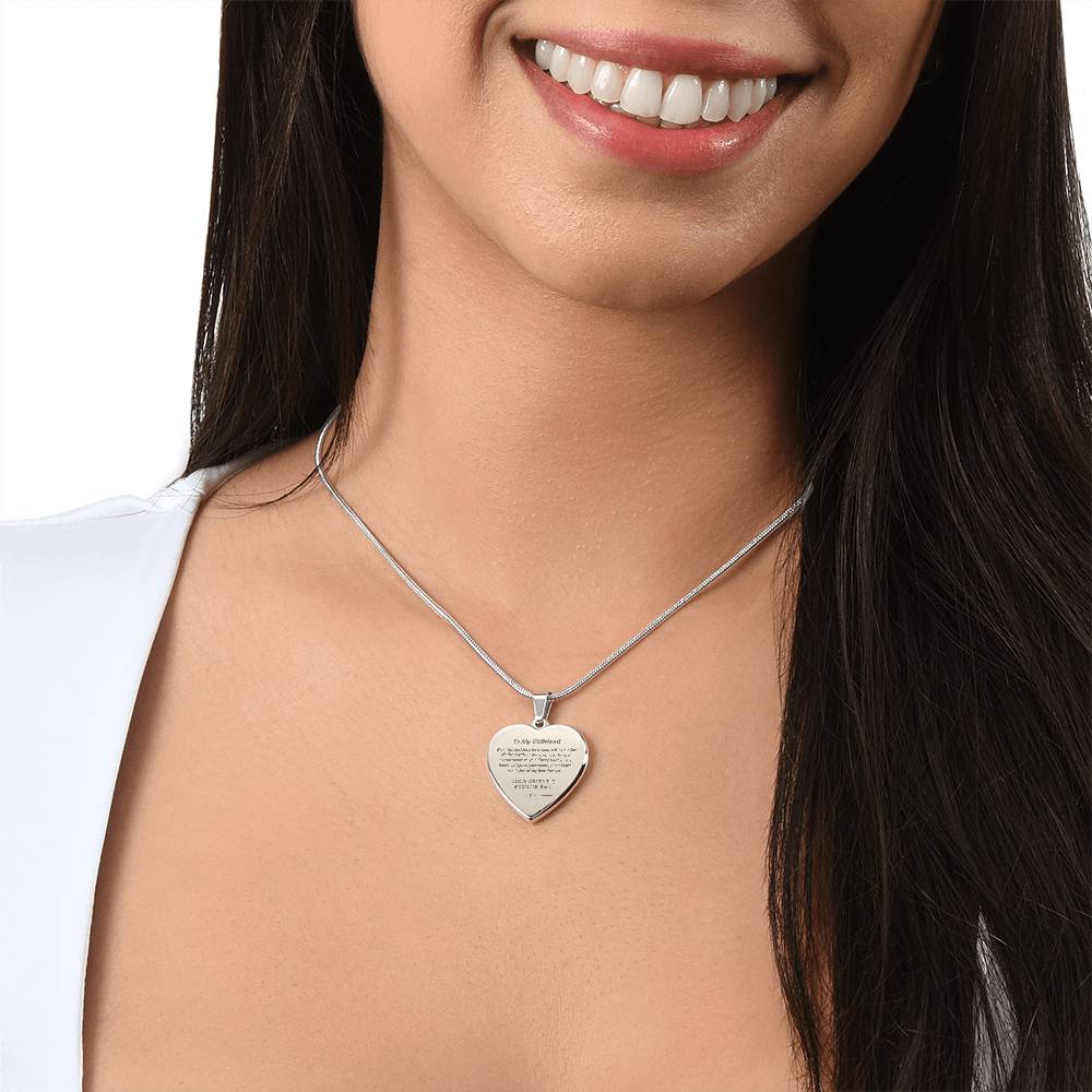 Heart-shaped silver pendant necklace with an engraved message hanging from a snake chain.