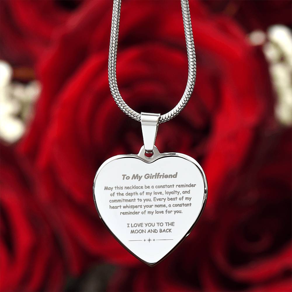 Heart-shaped silver pendant necklace with an engraved message hanging from a snake chain.