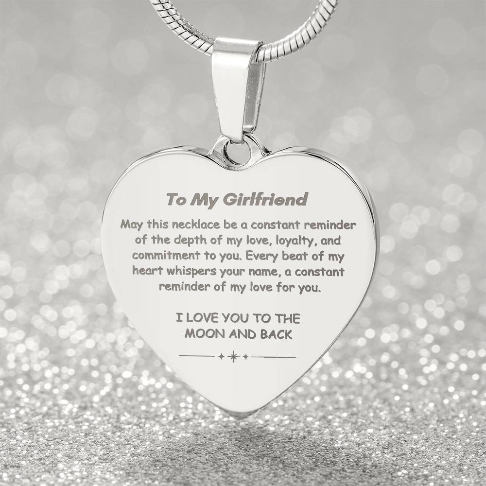 Heart-shaped silver pendant necklace with an engraved message hanging from a snake chain.