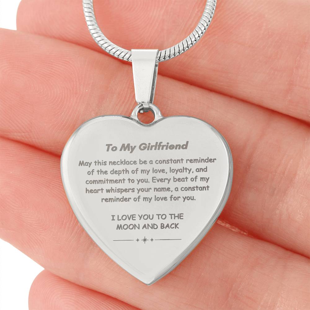 Heart-shaped silver pendant necklace with an engraved message hanging from a snake chain.