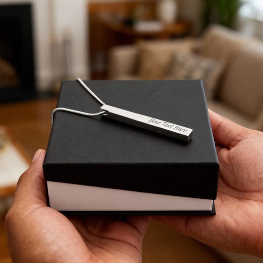 Black gift box with a white label held by hands in a blurred indoor setting