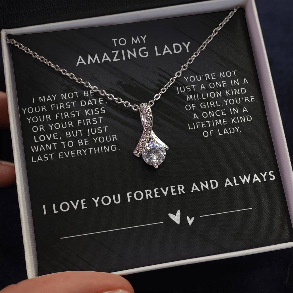 A necklace with a gemstone pendant in an open jewelry box with a loving message printed inside for girlfriend