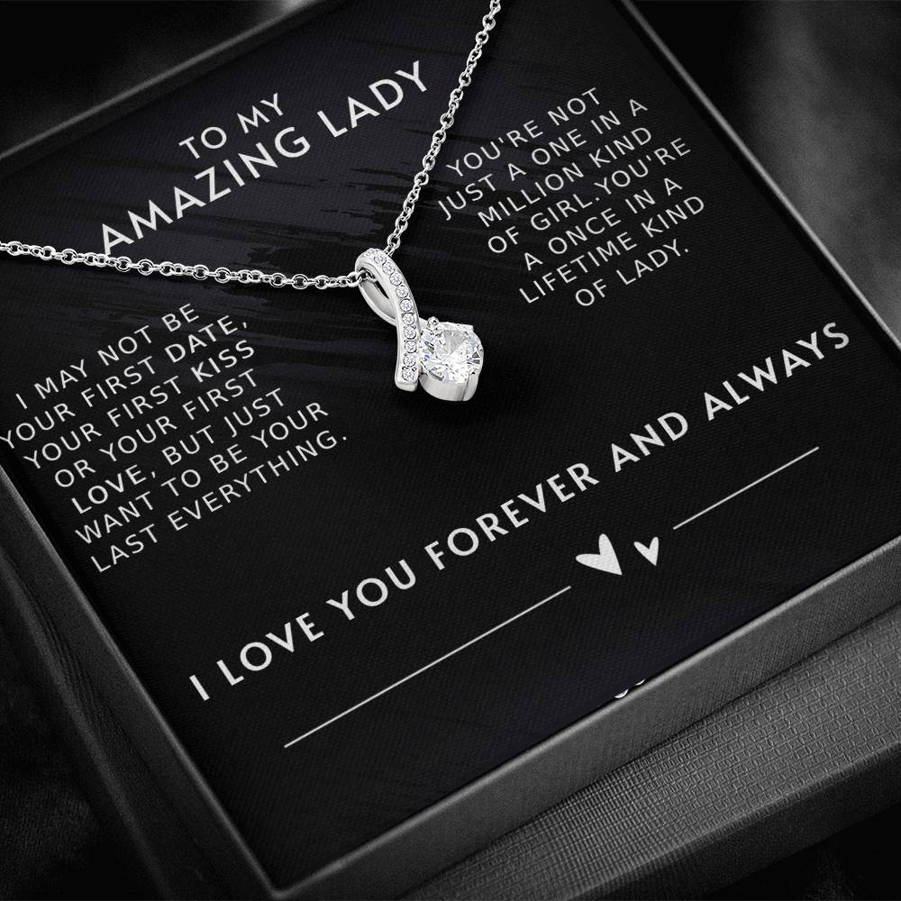 A necklace with a gemstone pendant in an open jewelry box with a loving message printed inside for girlfriend