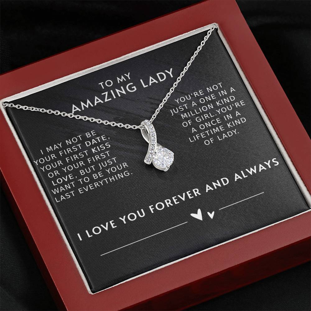 A necklace with a gemstone pendant in an open jewelry box with a loving message printed inside for girlfriend