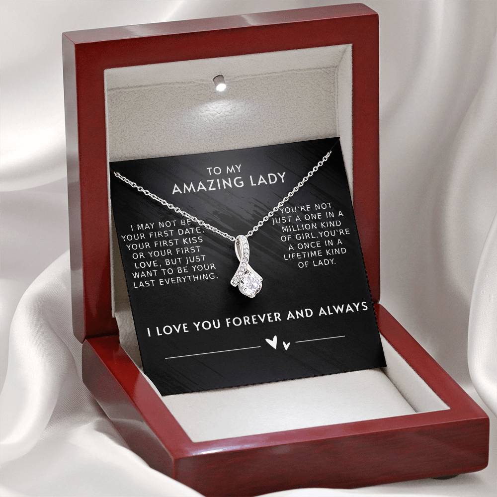 A necklace with a gemstone pendant in an open jewelry box with a loving message printed inside for girlfriend