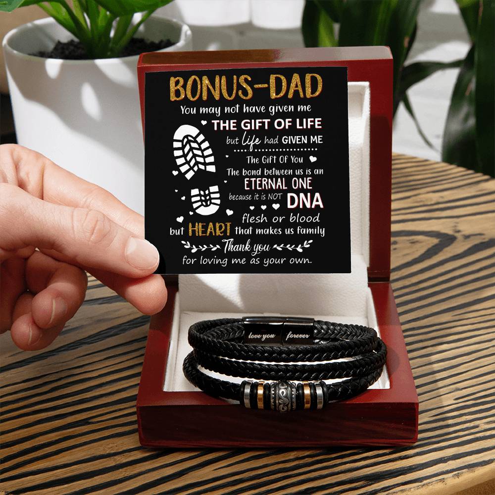 Hand holding a heartfelt card for a bonus dad next to a stylish black bracelet, perfect for showing appreciation and love